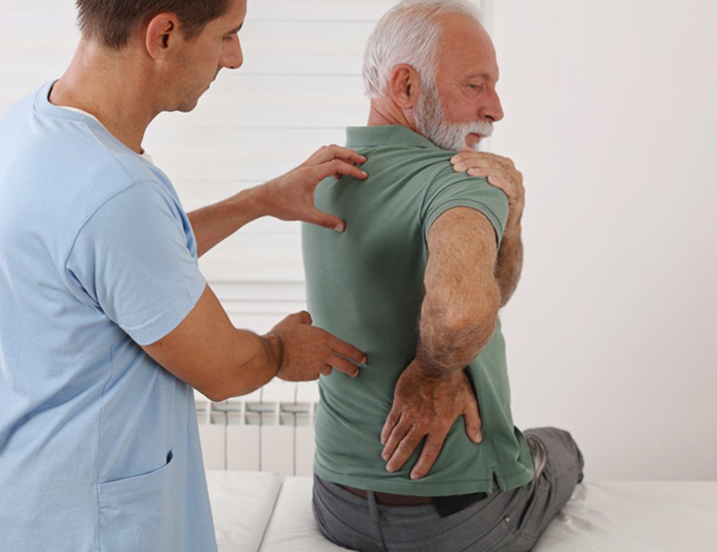Car-accident-chiropractor-evaluating-male-patient’s-back